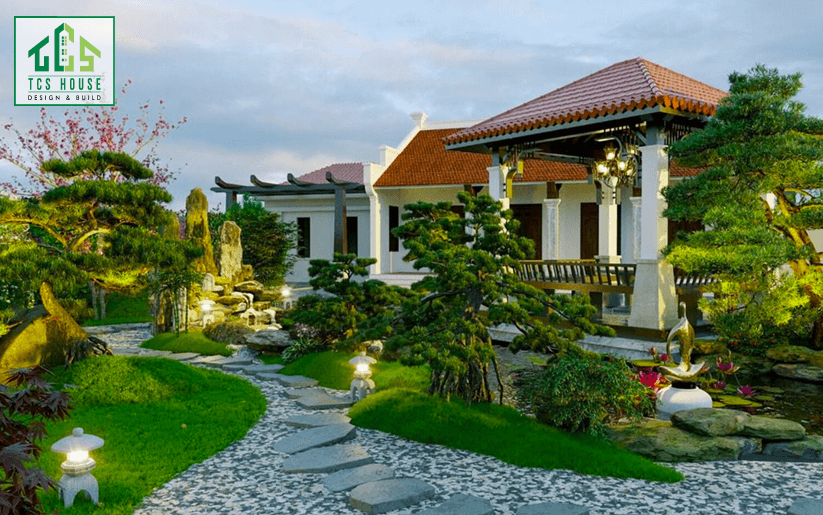 Mẫu 21: Nhà mái Nhật sân vườn rộng với lối đi lát đá, cây xanh bao quanh, tạo không gian sống xanh mát.
